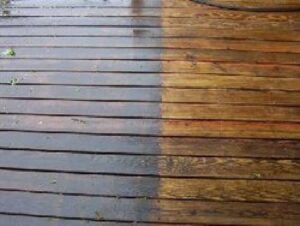 Wooden deck shown partially cleaned; left side is dirty and dark, right side is clean and lighter in color.