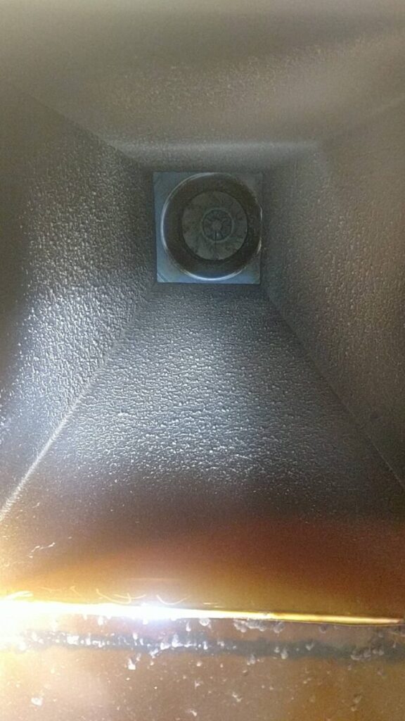 Close-up view of the inside of a black metal air vent or duct with a circular fan component at the center.