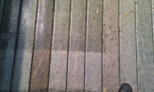 Close-up of outdoor wooden steps showing a clear contrast between dirty and recently cleaned sections.