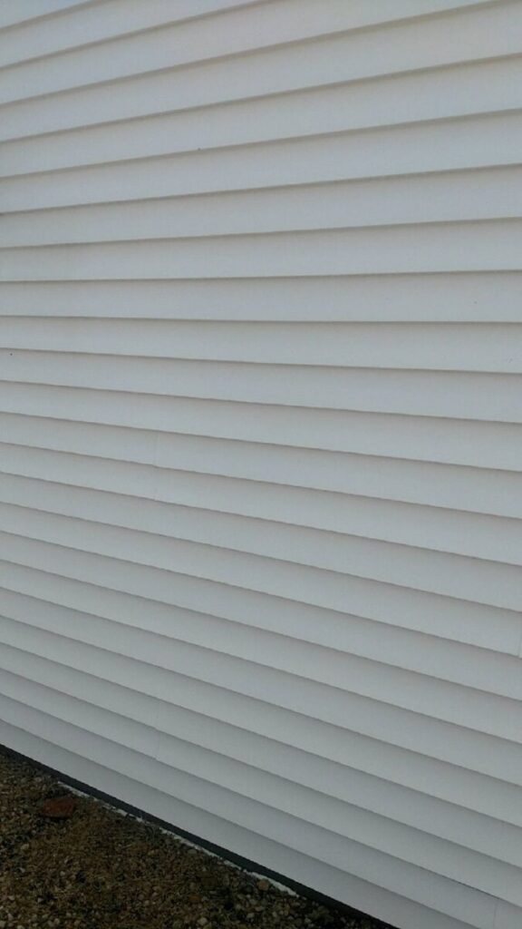 White vinyl siding on the exterior wall of a building, photographed from a slight angle.