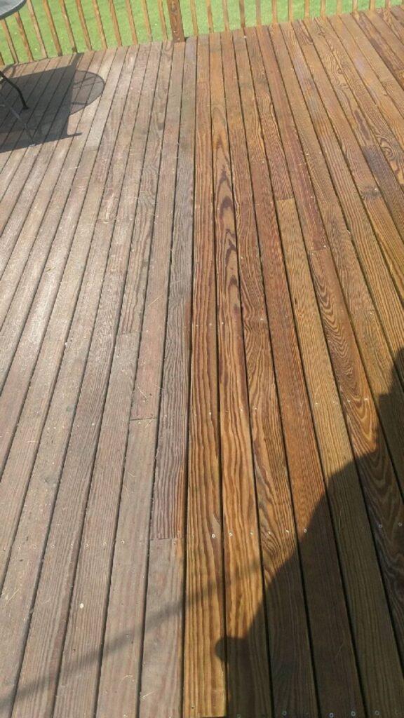 Wooden deck with two distinct sections: one side weathered and faded, the other side newly cleaned or stained.